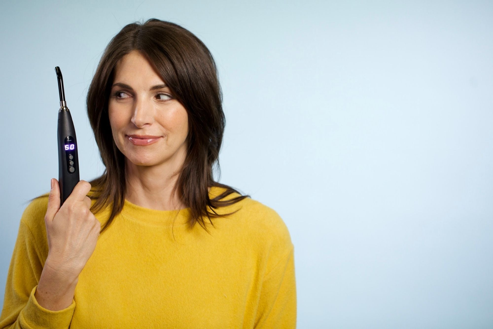 A woman holding a light therapy device for canker sores and to help with pregnancy