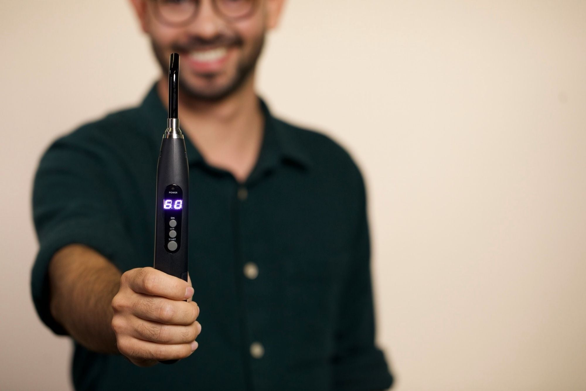 A man wearing a black shirt holds the Luminance RED Canker Sore device to treat canker sores in his throat.