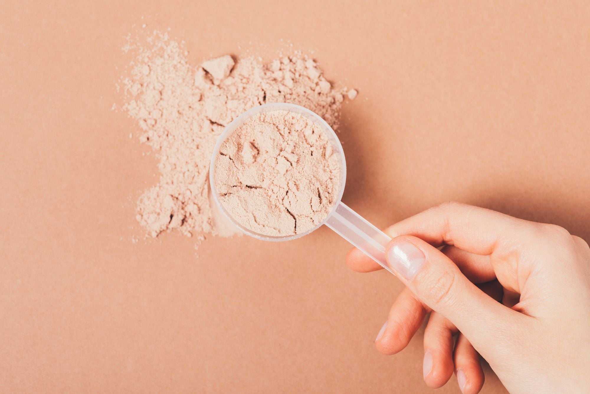 A woman holding a scoop of pre-workout, while wondering if pre-workout causes acne.