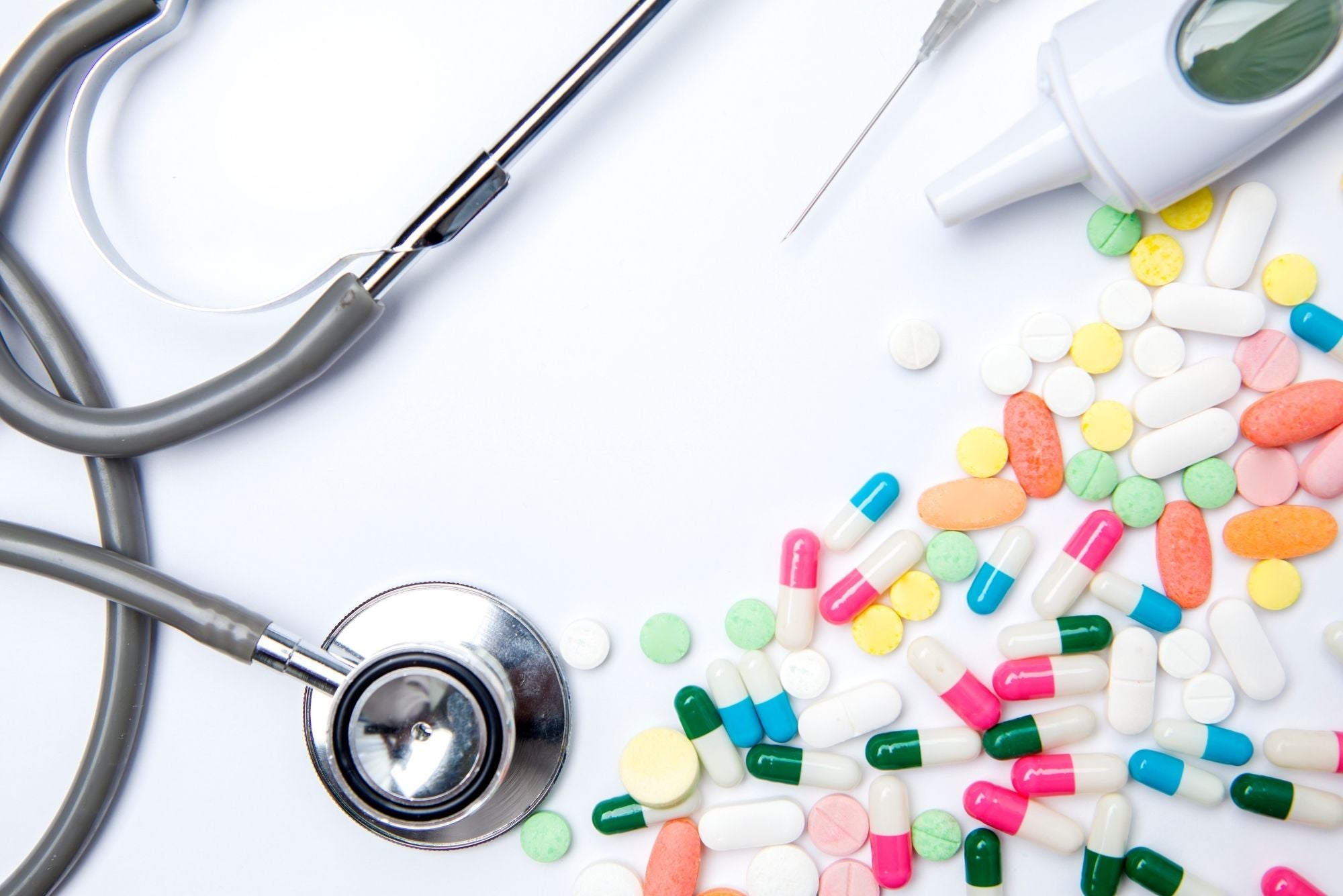 A stethoscope, pills, syringe, and gel on white background, symbolizing the link between chronic canker sores and autoimmune disease.