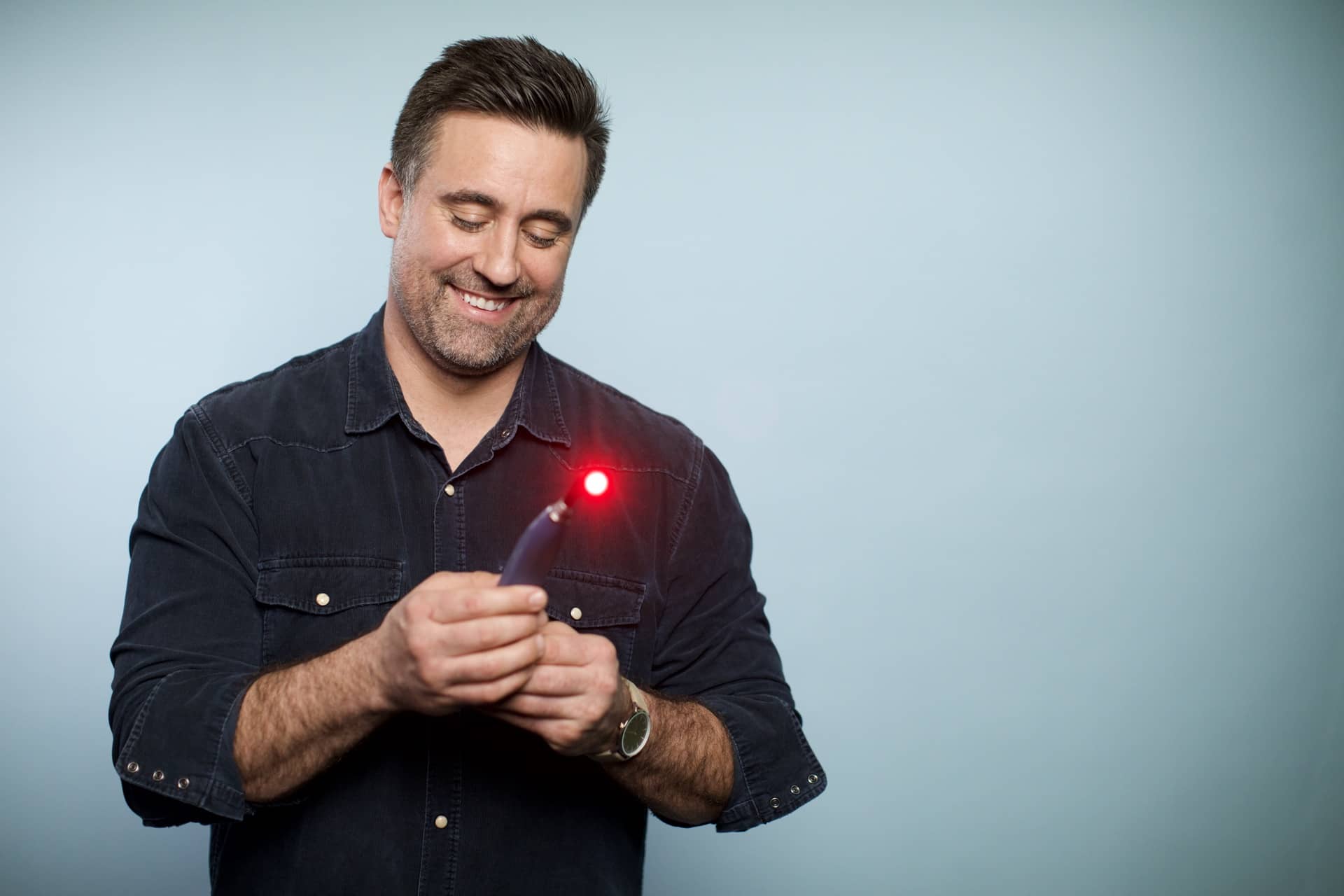 A man holds his Luminance RED device, curious about how many people have herpes.