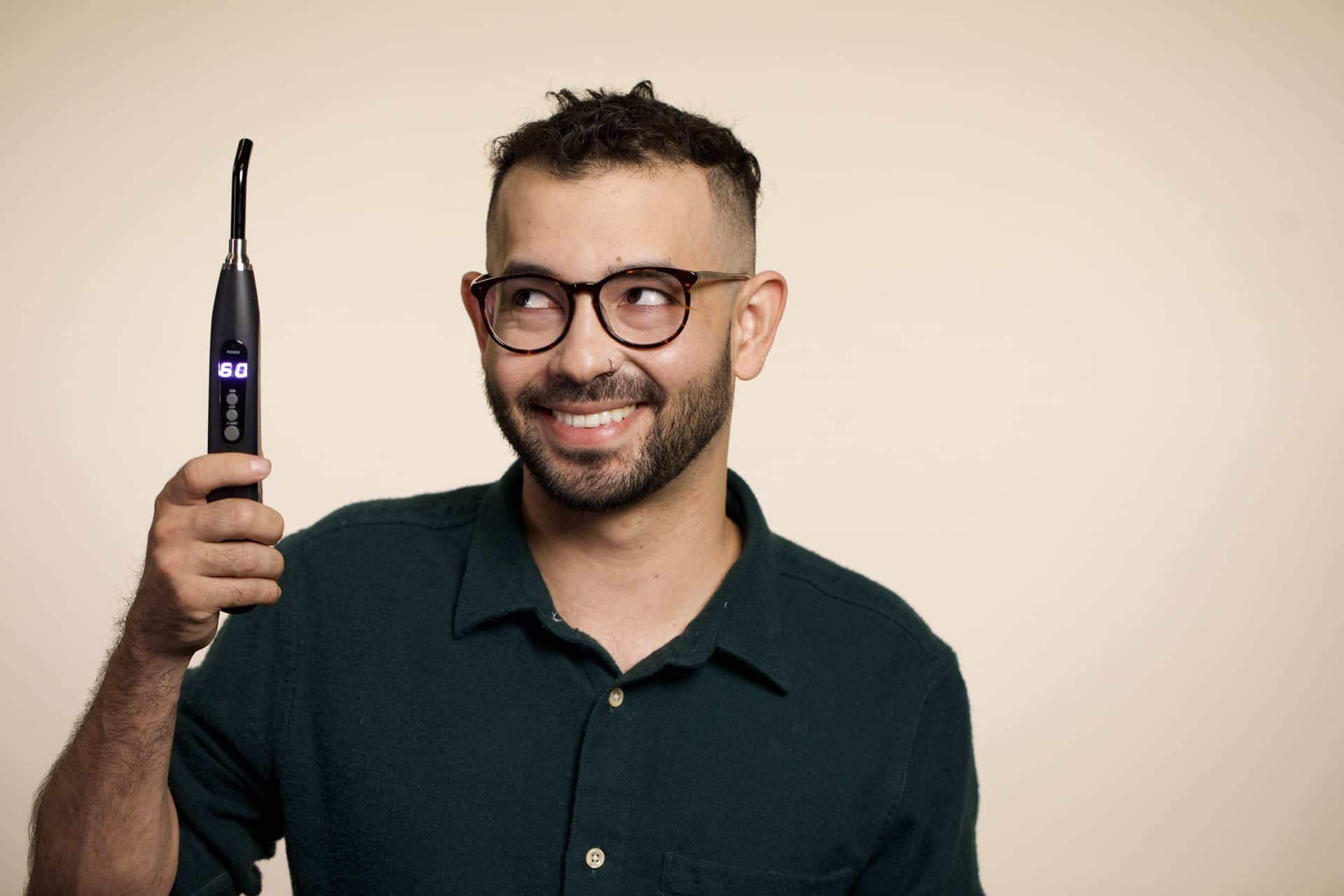 A smiling man with glasses holds up a light therapy device in an article on oral yeast infections and canker sores.