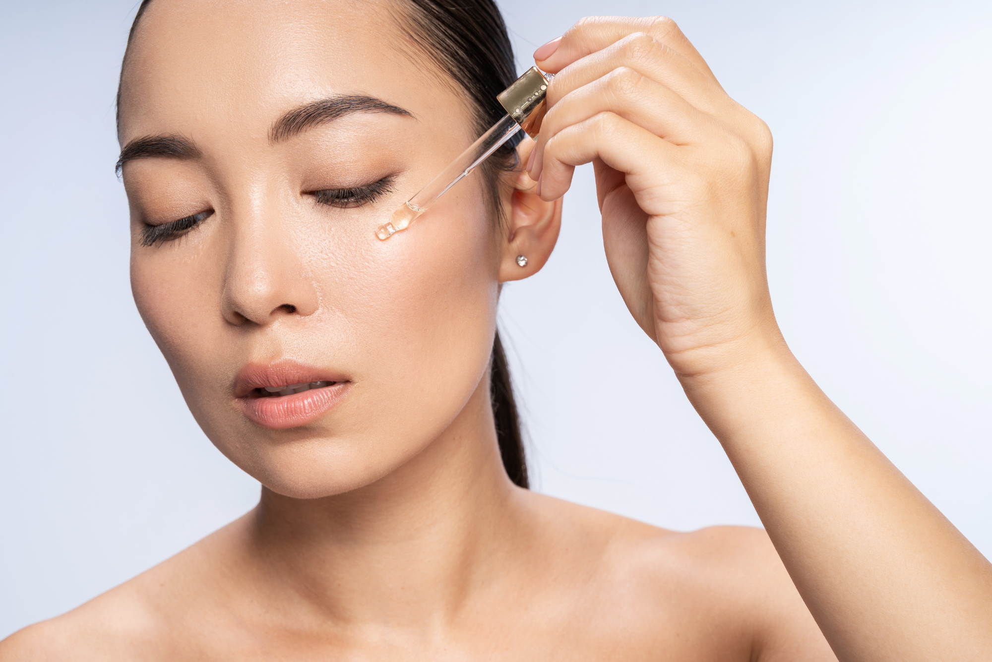 After finding the best serum to use with her LED light therapy wand, a woman applies the product to her cheek with a dropper.